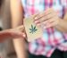Woman give to buyer paper bag of drugs. Marijuana leaf close-up on paper bag.